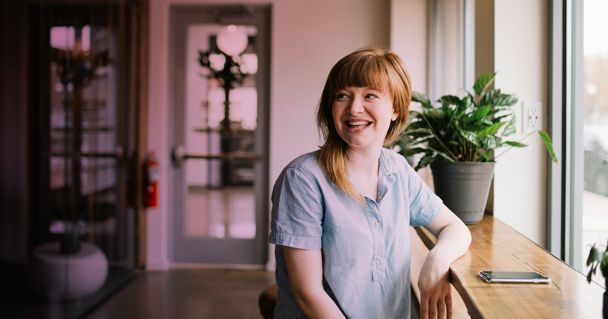 Illustration photo: a happy office person sitting at a bench desk in a modern office